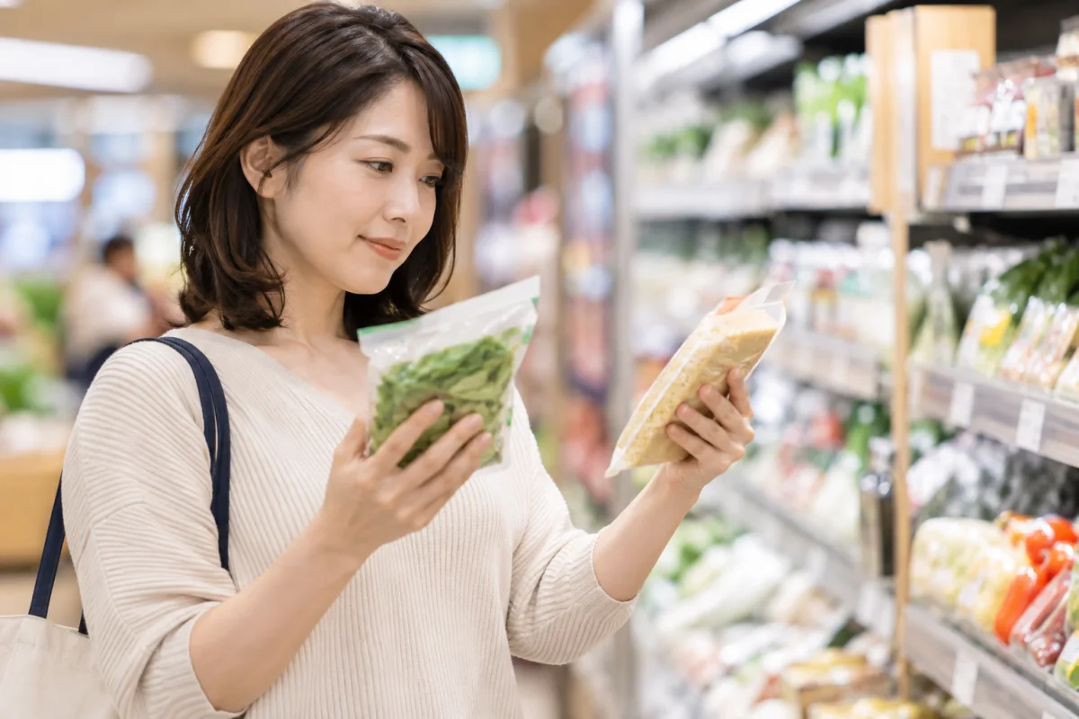 スーパーで二つの食品を比較して選ぶ女性